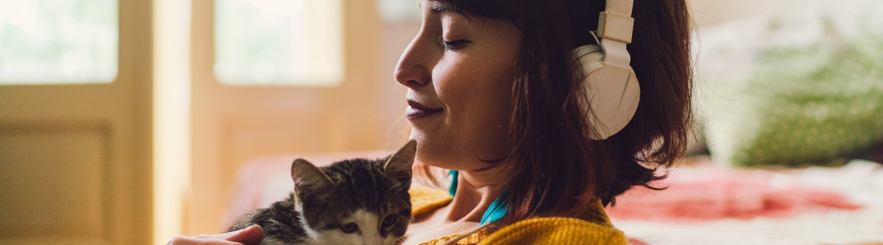 Woman listening to music and holding kitten