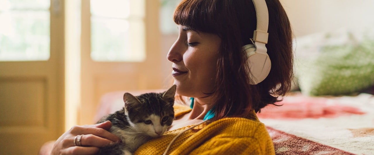 Woman listening to music and holding kitten