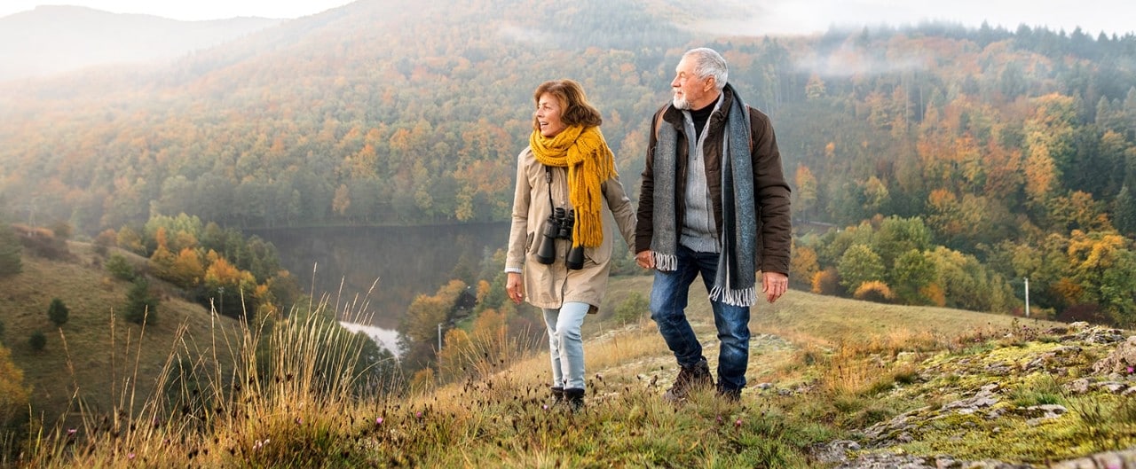 Senior couple hiking in hills overlooking river
