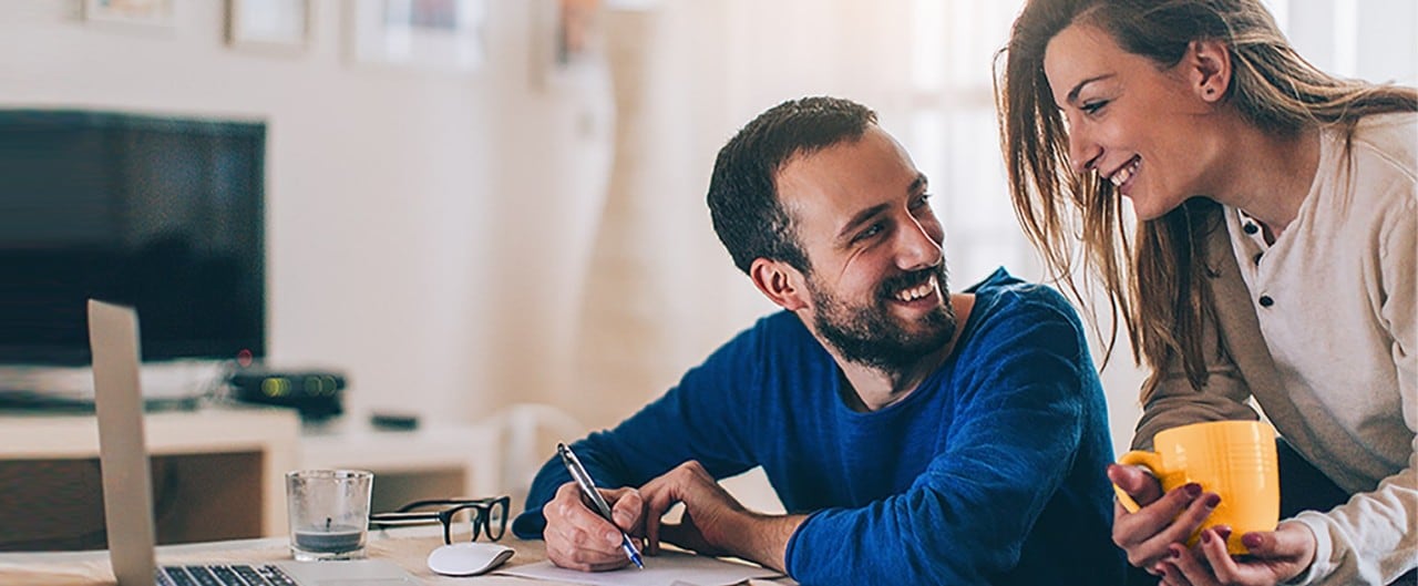 Couple at desk with laptop reviewing financial documents