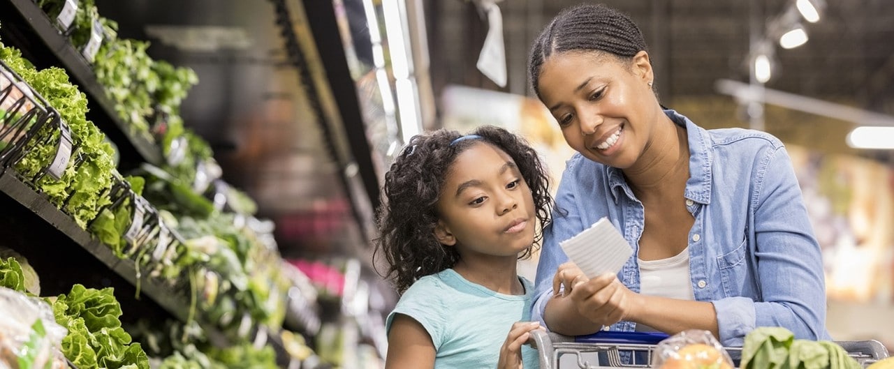 African-American mother and daughter grocery shopping in produce aisle