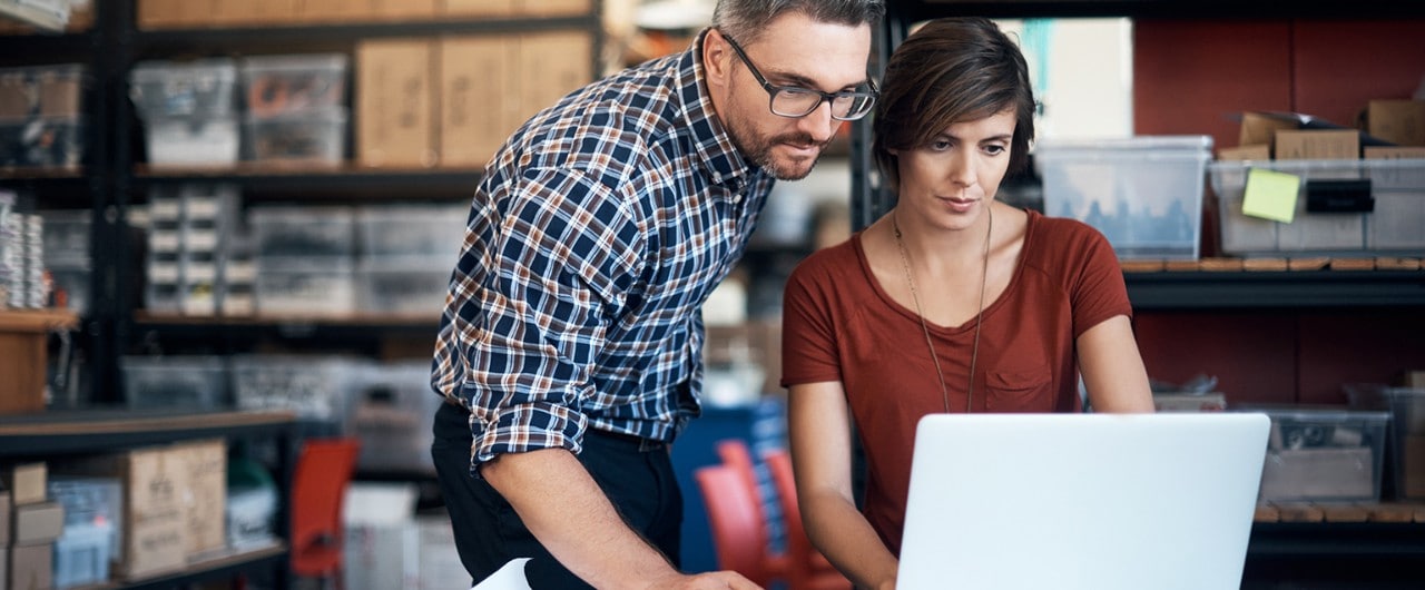 Business partners in warehouse using laptop