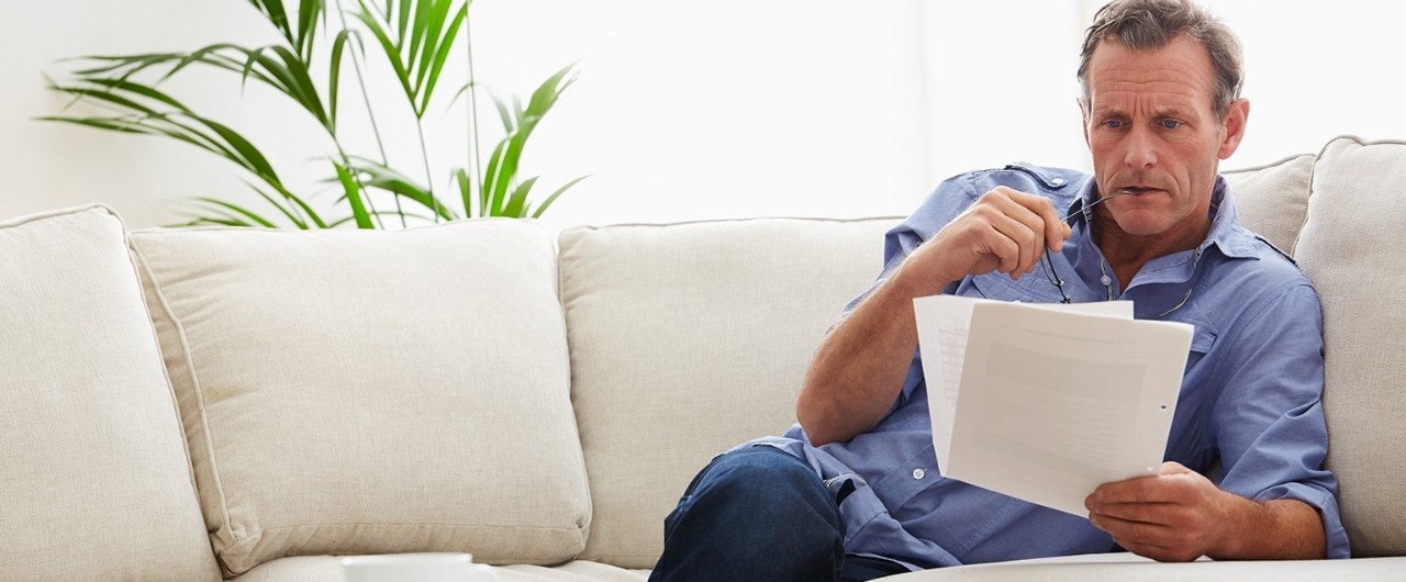 Middle-aged man reviewing documents on sofa