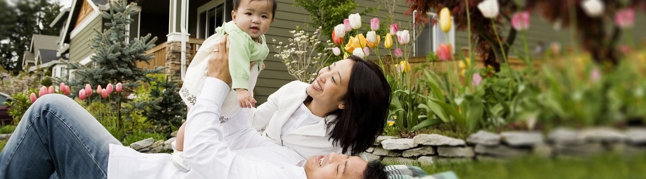 Young family relaxing in yard with tulips and home in the background