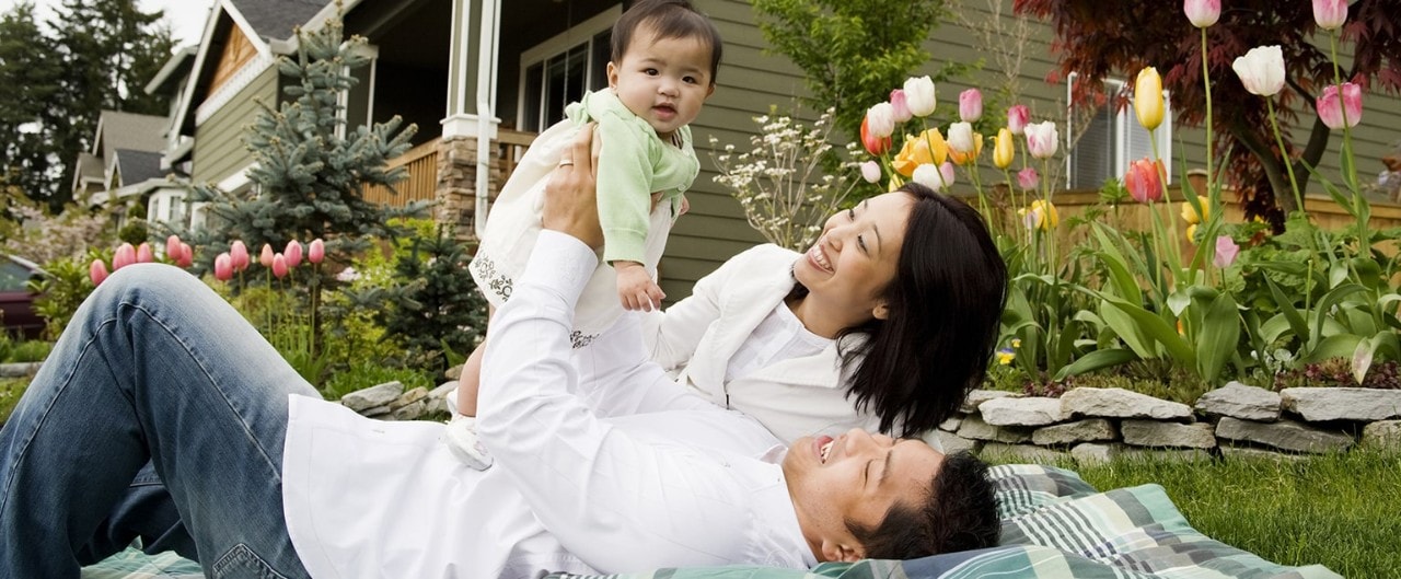 Young family relaxing in yard with tulips and home in the background