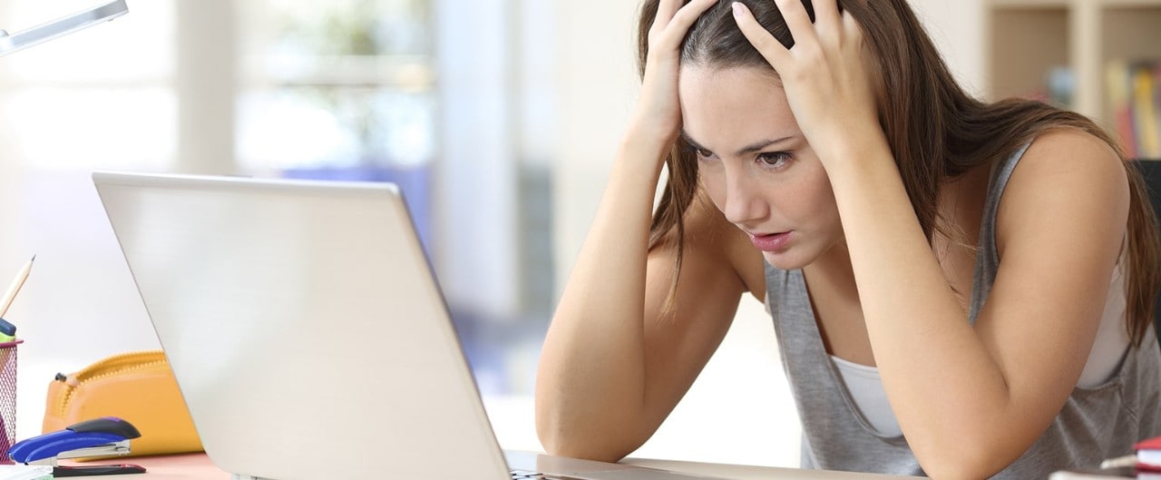 Frustrated female college student looking at laptop monitor