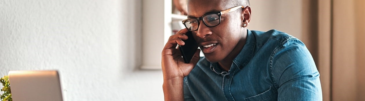 African-American man looking at laptop talking on the phone