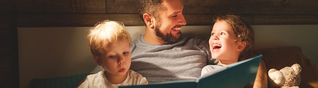 Father reading bedtime story to his young children