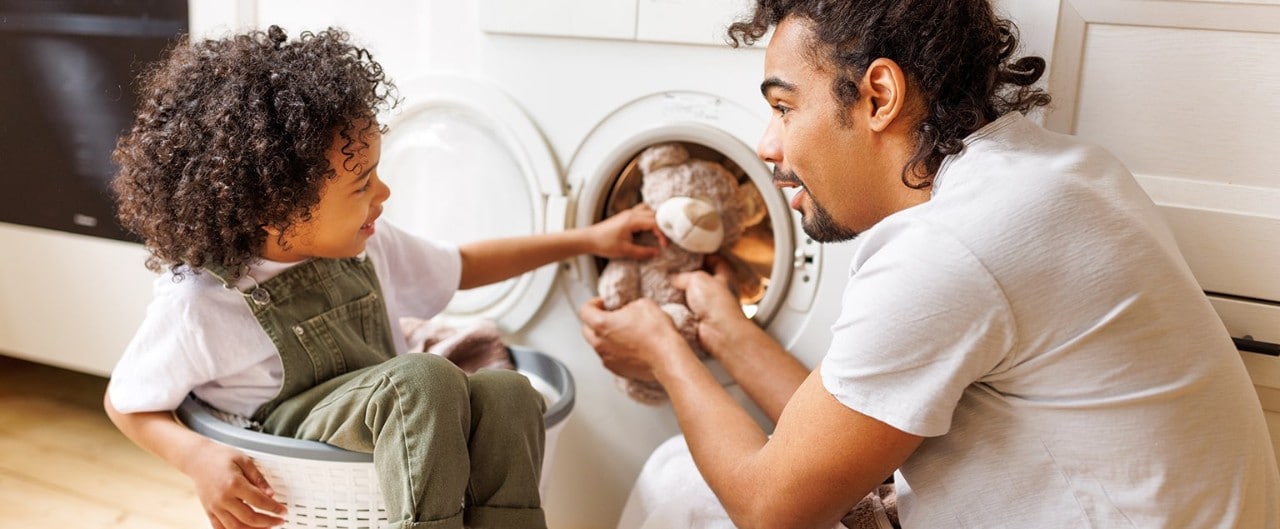 Father and young child doing laundry