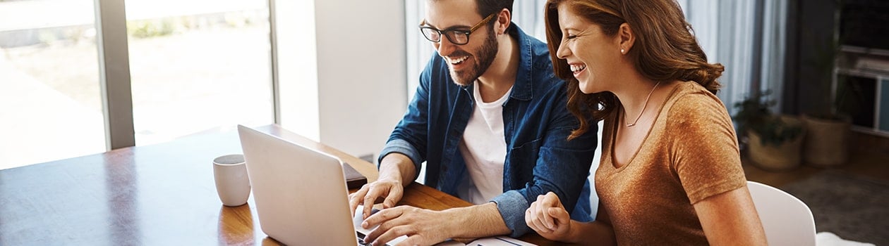 Young couple paying bills online at kitchen table