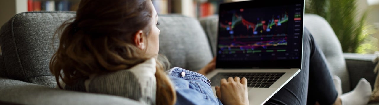 Woman on couch reviewing financial data on laptop