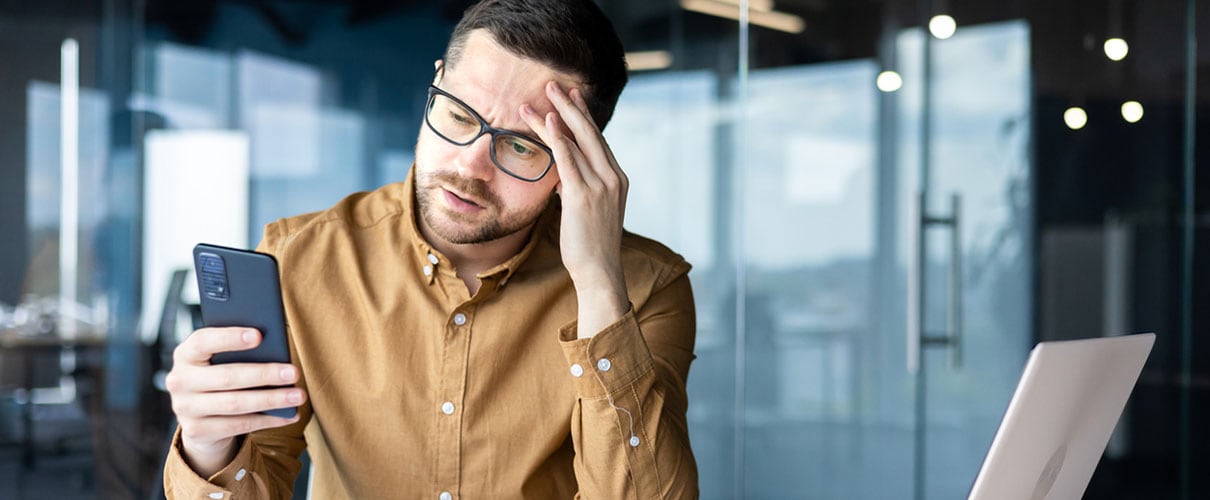 Young Caucasian man looking at smartphone with worried expression