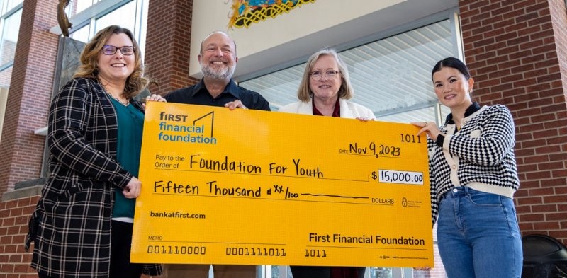 First Financial employees hold a donation check for $15,000