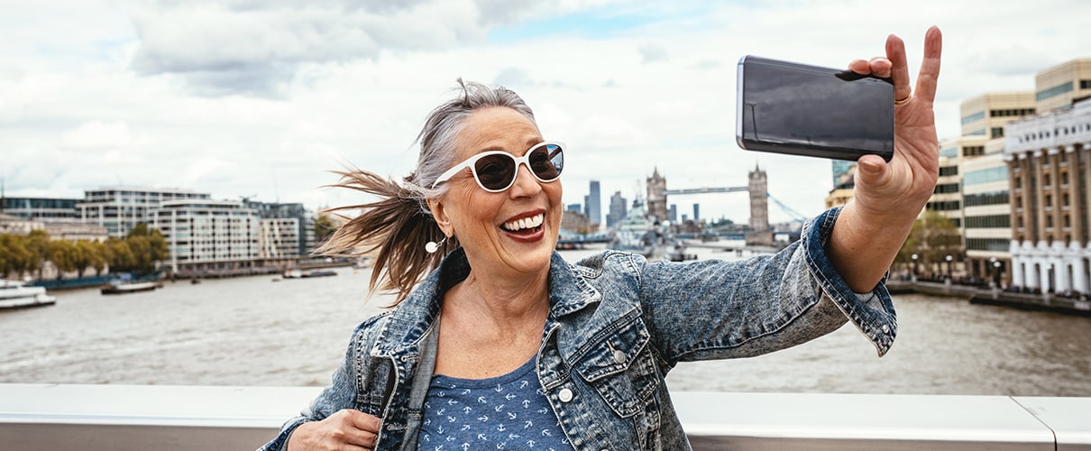Mature woman on vacation taking selfie on bridge