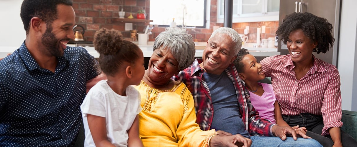 Happy African-American family and grandparents sitting on couch