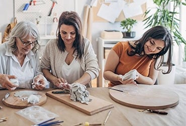 Woman working on pottery project with her mother and teenaged daughter